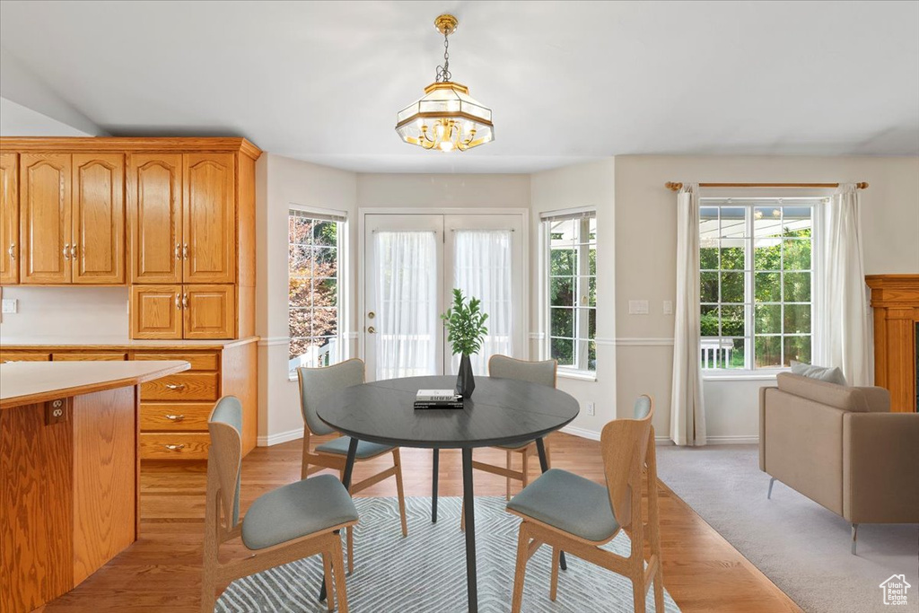 Dining space featuring a healthy amount of sunlight, light hardwood / wood-style floors, and an inviting chandelier