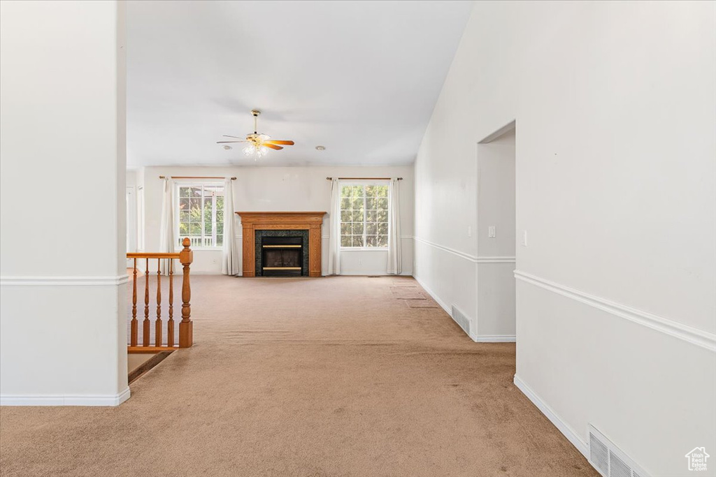 Unfurnished living room featuring carpet and ceiling fan