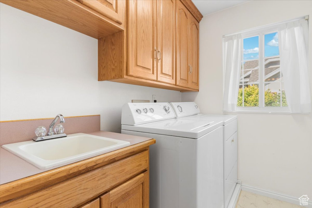 Laundry area featuring sink, cabinets, washing machine and dryer, and light tile patterned flooring