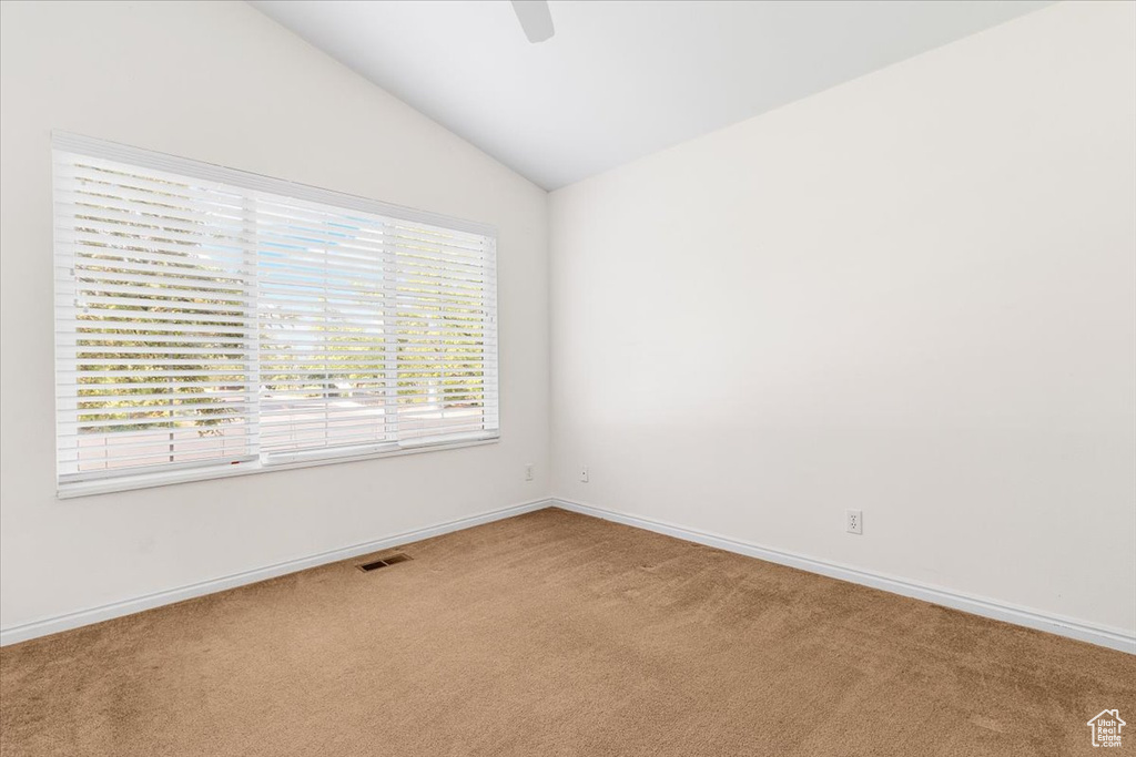 Carpeted empty room featuring lofted ceiling