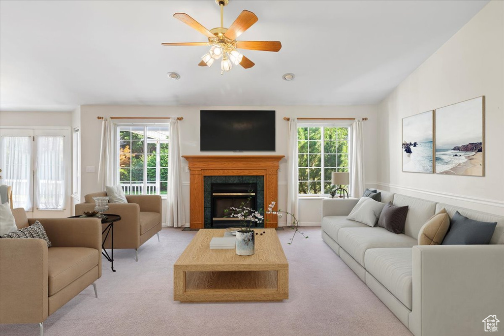 Living room with a fireplace, ceiling fan, carpet flooring, and a healthy amount of sunlight