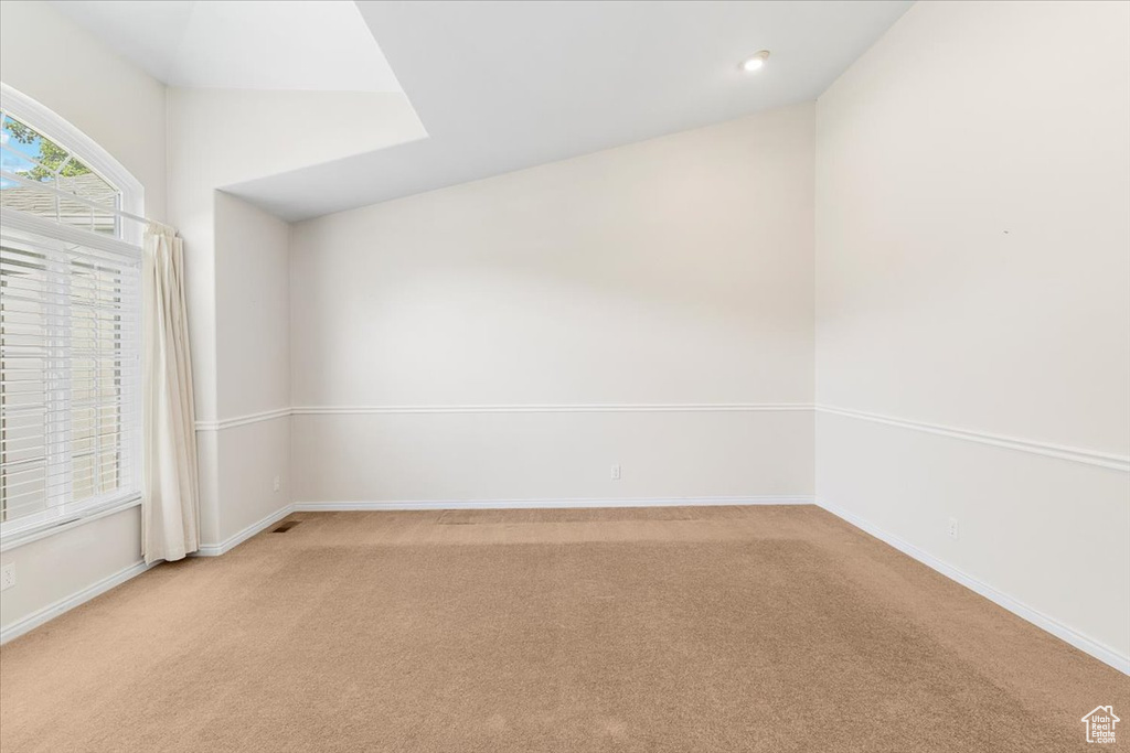 Carpeted empty room featuring vaulted ceiling