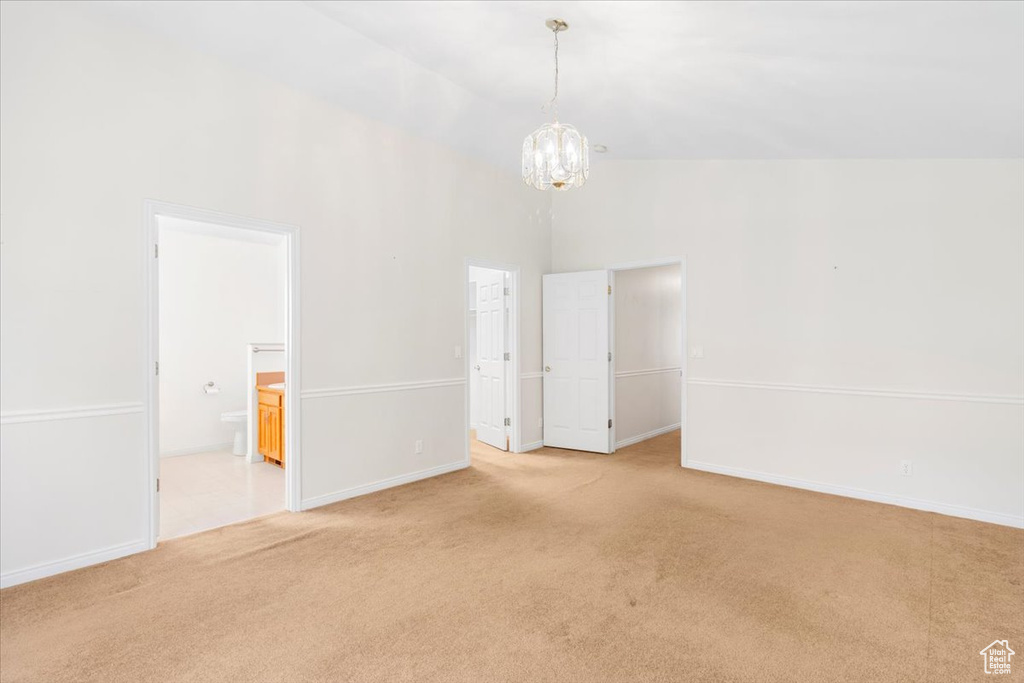 Unfurnished room with light carpet, a notable chandelier, and high vaulted ceiling