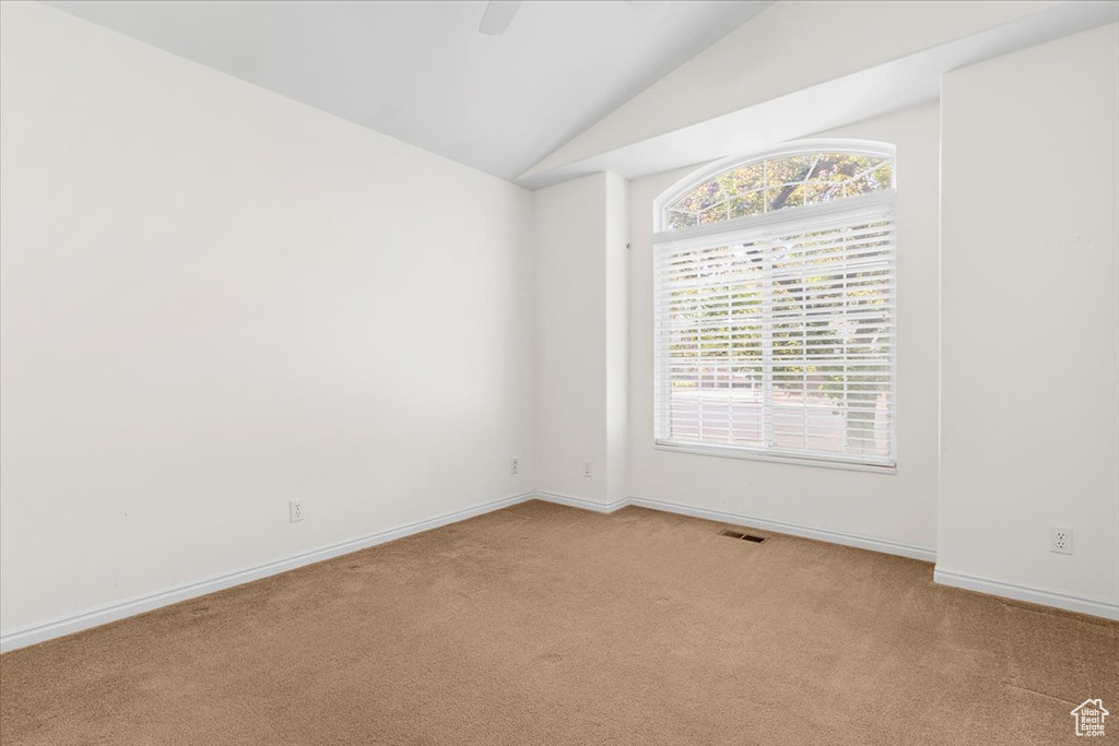 Carpeted spare room featuring lofted ceiling