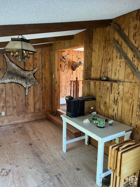 Unfurnished dining area with beam ceiling, a textured ceiling, and wooden walls