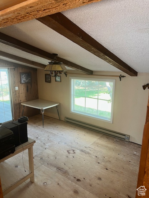 Interior space featuring beamed ceiling, a wealth of natural light, a textured ceiling, and a baseboard heating unit