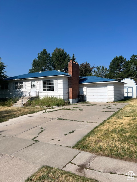 View of front of home with a garage, a front lawn, and an outdoor structure