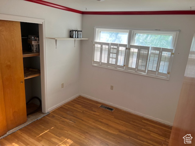 Unfurnished bedroom with lofted ceiling and hardwood / wood-style floors