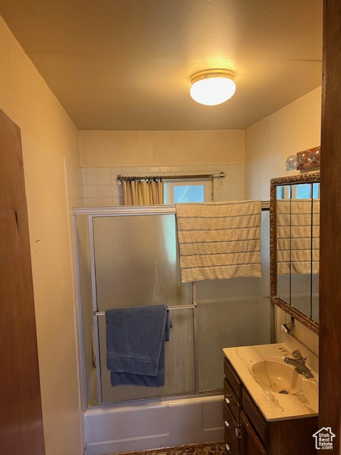 Bathroom featuring vanity and bath / shower combo with glass door