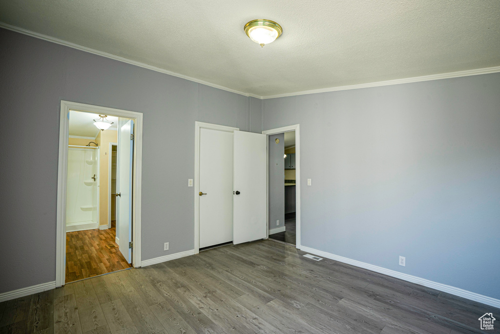 Unfurnished bedroom with wood-type flooring and crown molding