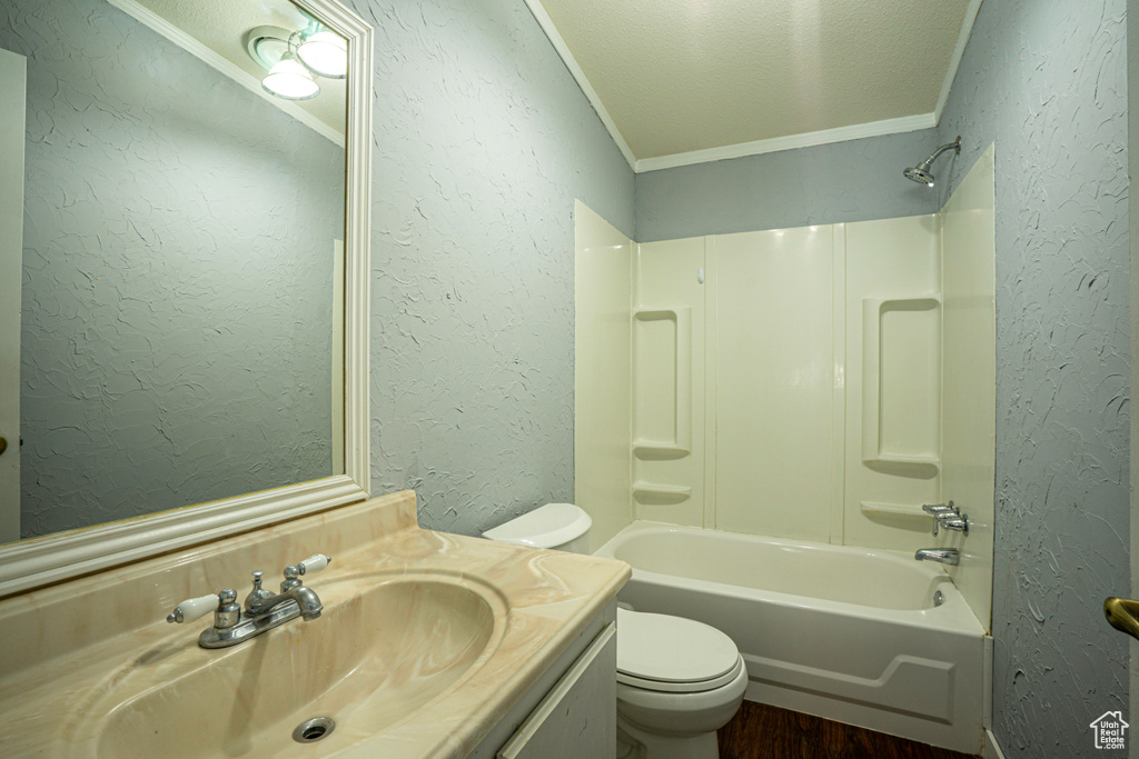 Full bathroom with crown molding, bathtub / shower combination, toilet, vanity, and hardwood / wood-style flooring