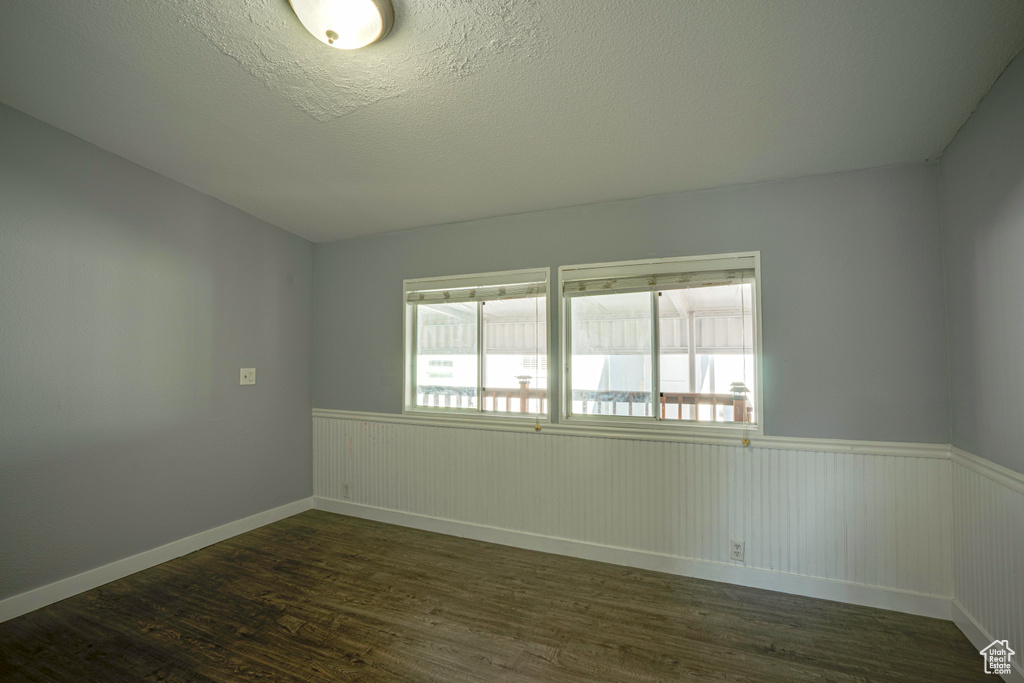 Unfurnished room with dark hardwood / wood-style floors and a textured ceiling