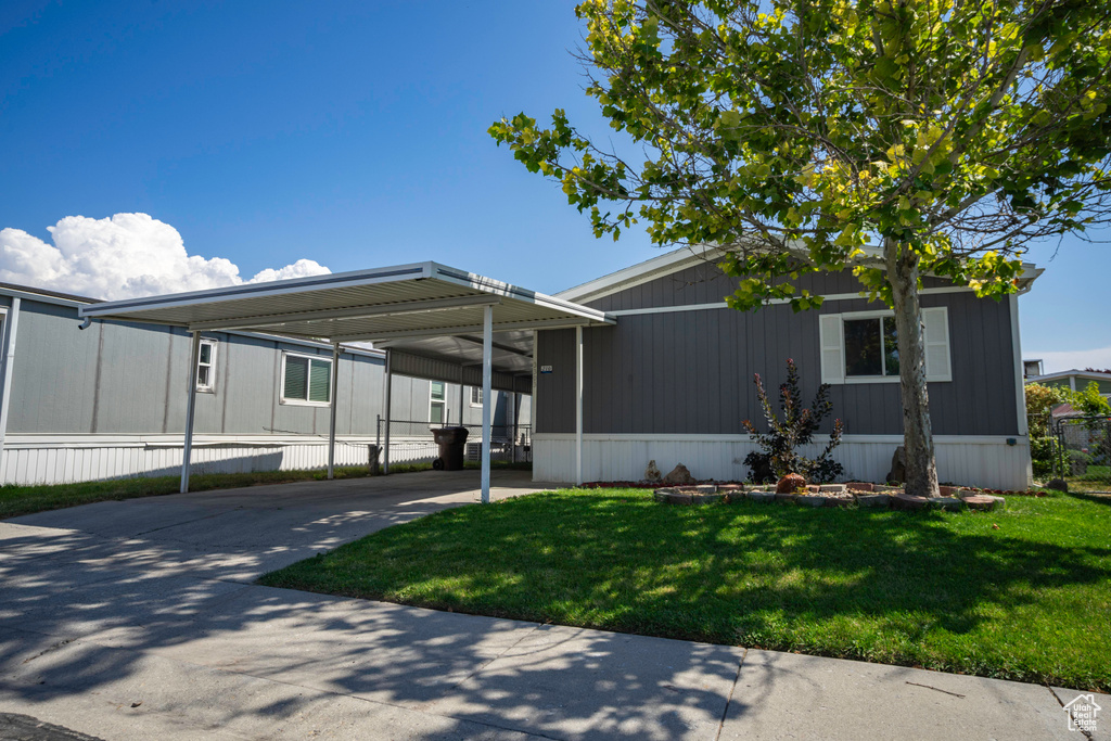 Manufactured / mobile home featuring a carport and a front lawn