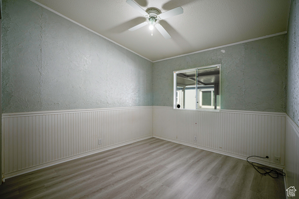 Empty room featuring a textured ceiling, crown molding, hardwood / wood-style floors, and ceiling fan