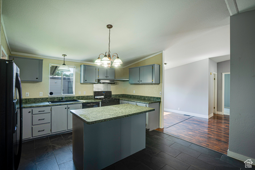 Kitchen featuring range with gas stovetop, dark hardwood / wood-style flooring, pendant lighting, black fridge, and sink