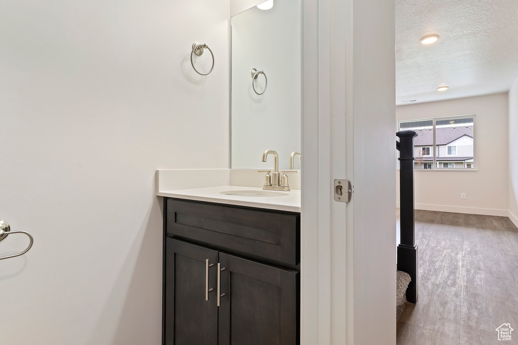 Bathroom with a textured ceiling, vanity, and wood-type flooring