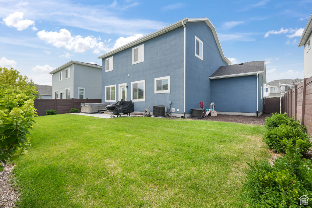 Back of house with central AC unit, a patio area, and a yard