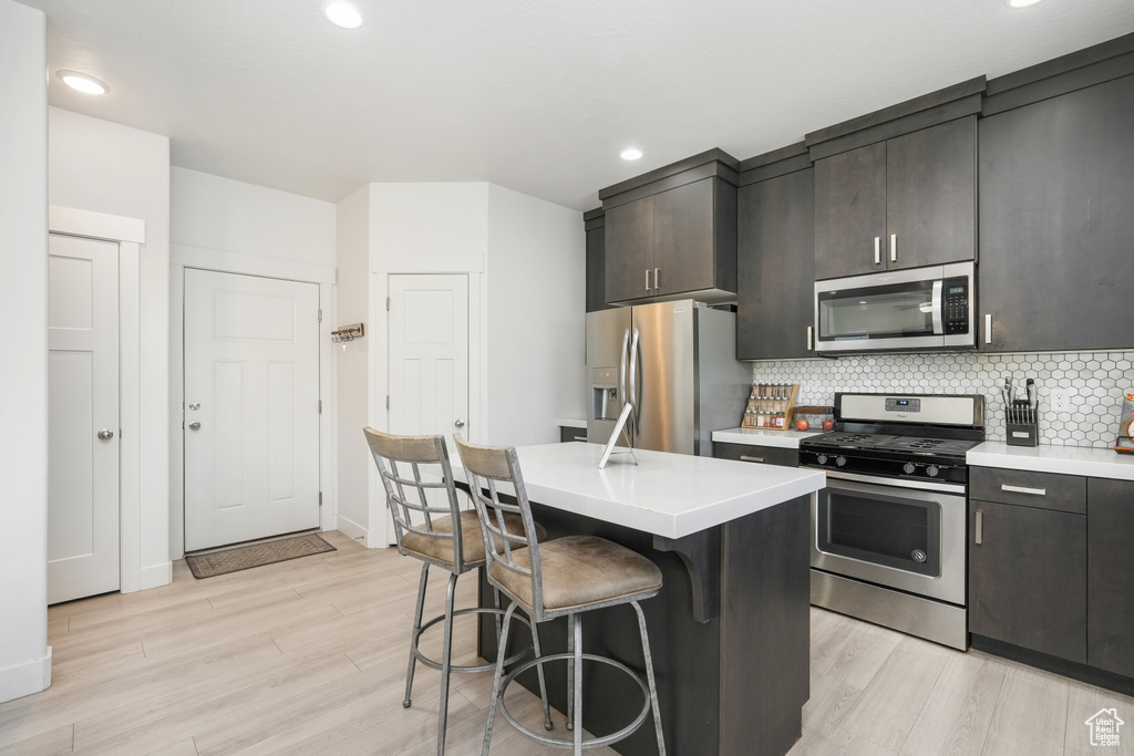 Kitchen featuring a center island, appliances with stainless steel finishes, backsplash, and light hardwood / wood-style floors