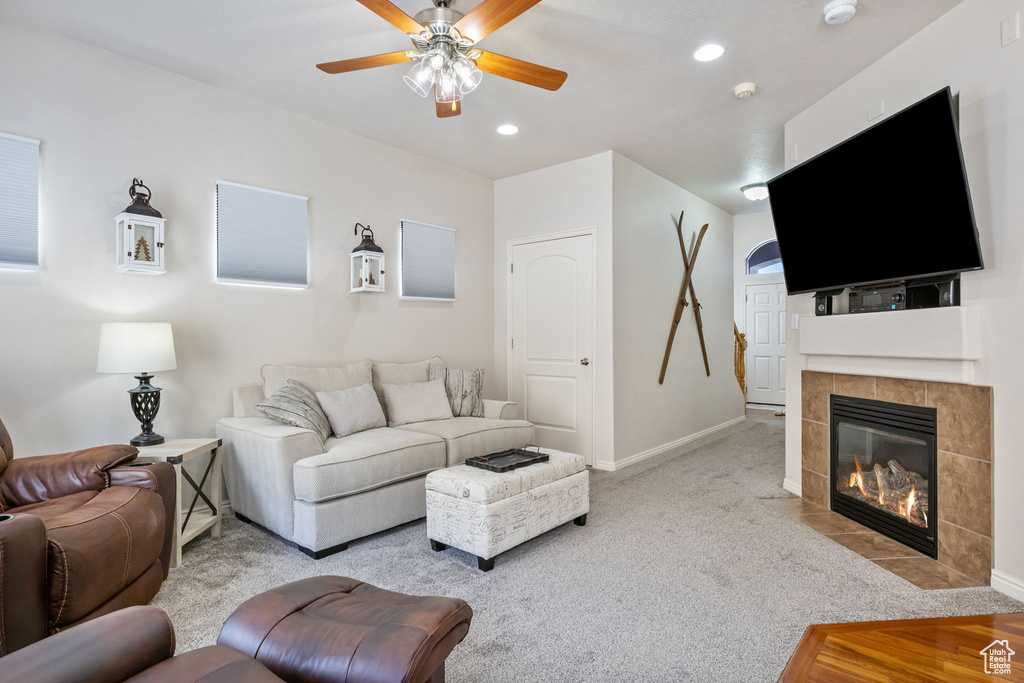 Living room featuring a fireplace, light colored carpet, and ceiling fan