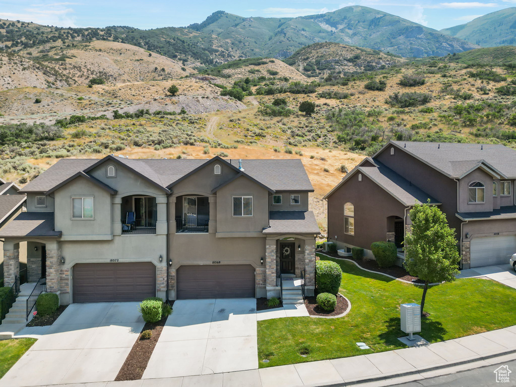 View of front facade with a mountain view, a garage, and a front lawn