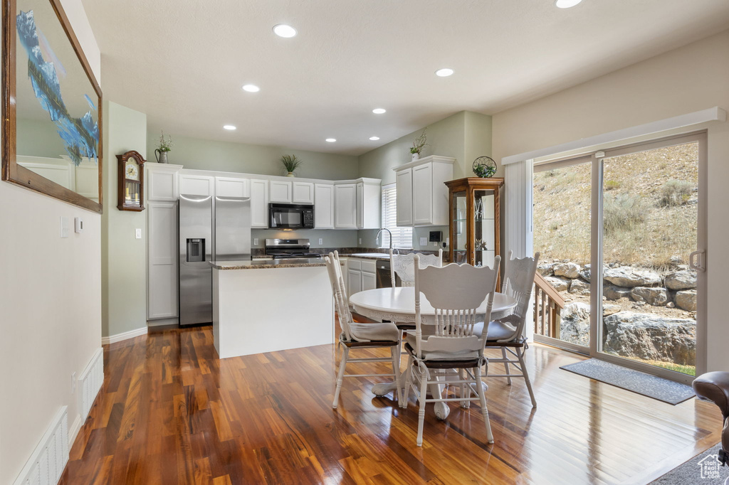 Kitchen with white cabinetry, wood-type flooring, stove, and plenty of natural light