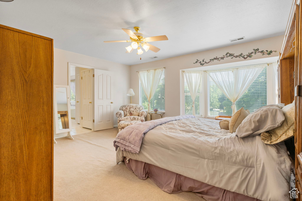 Bedroom with a closet, light colored carpet, and ceiling fan