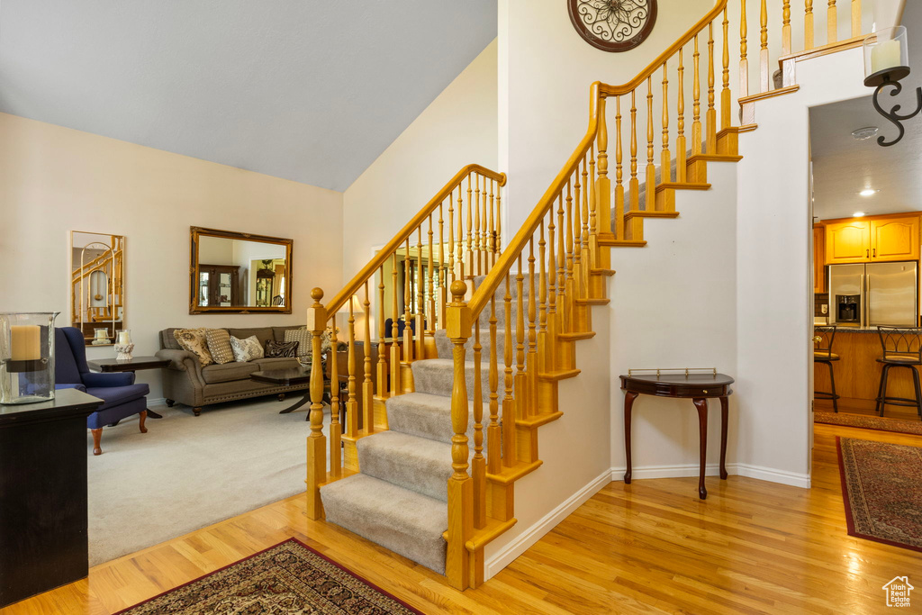 Stairway featuring light carpet and vaulted ceiling