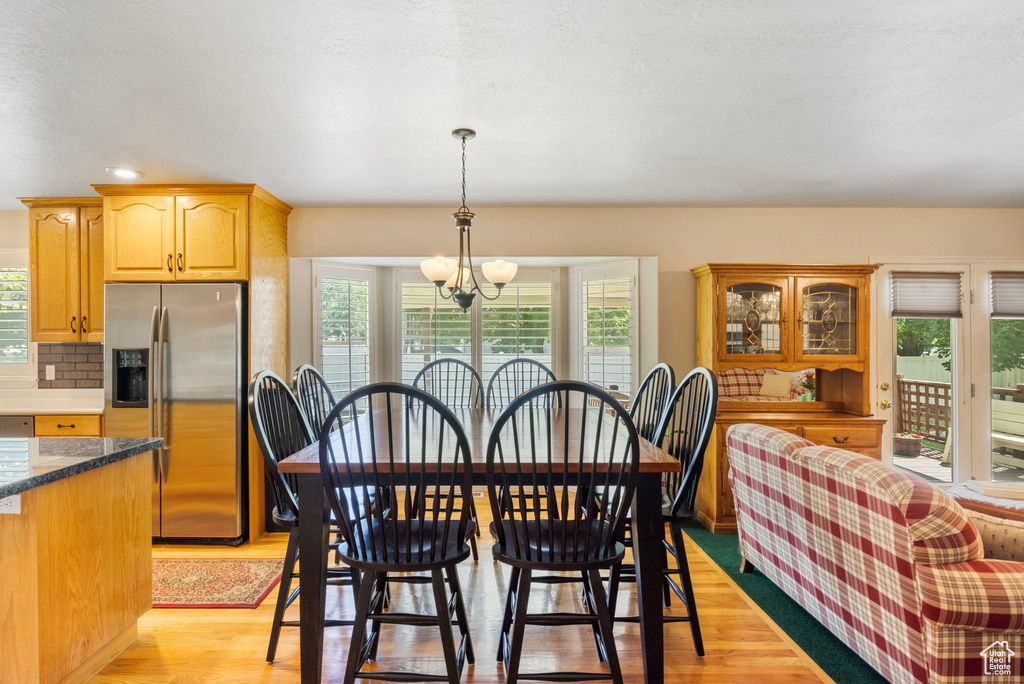 Dining space with light hardwood / wood-style floors, a notable chandelier, and plenty of natural light