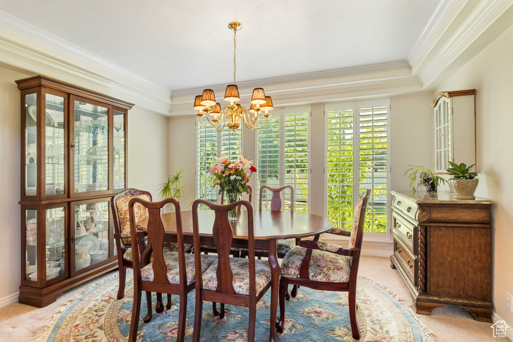 Dining space with a notable chandelier, light colored carpet, and ornamental molding