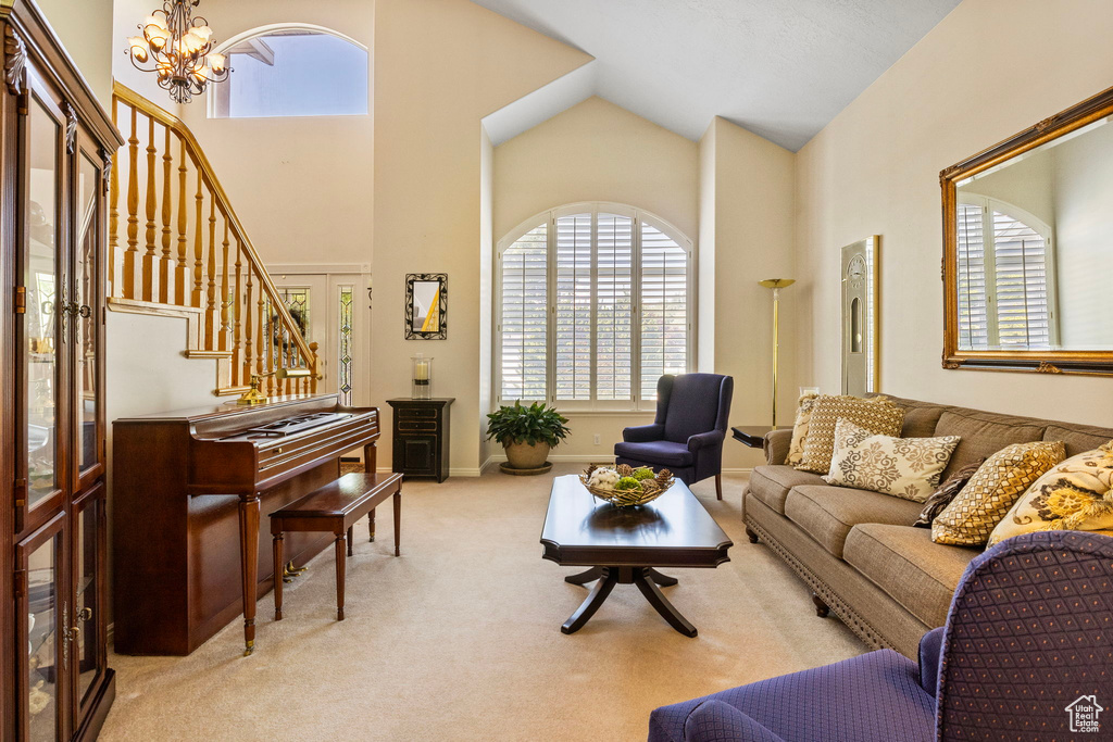 Carpeted living room with high vaulted ceiling and an inviting chandelier