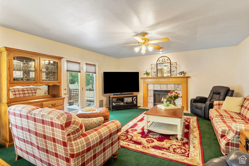 Carpeted living room featuring a tiled fireplace and ceiling fan