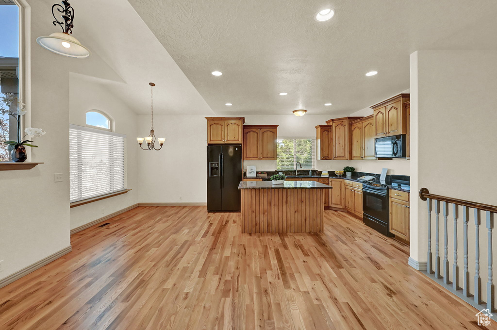 Kitchen with light hardwood / wood-style floors, sink, black appliances, and a center island