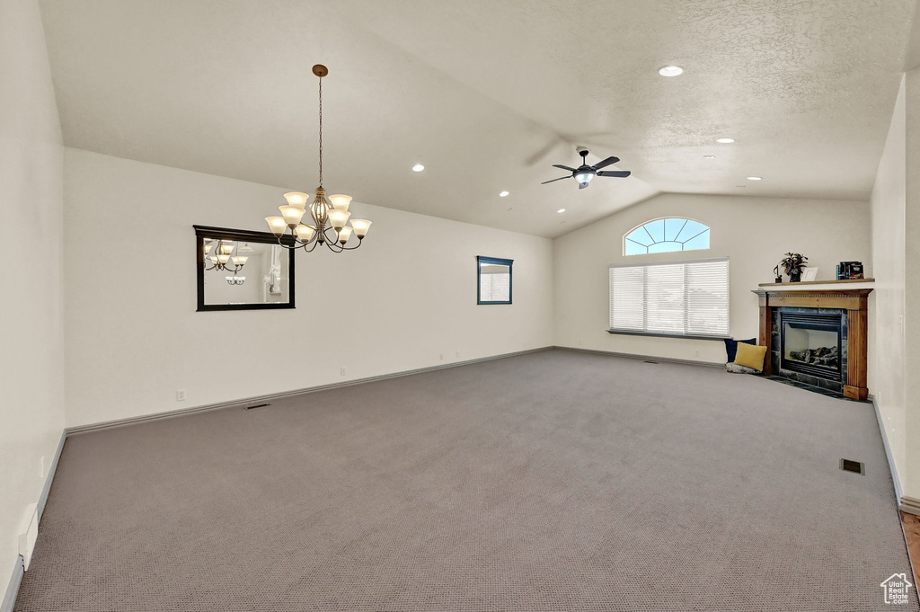 Unfurnished living room with a textured ceiling, ceiling fan with notable chandelier, lofted ceiling, and carpet flooring