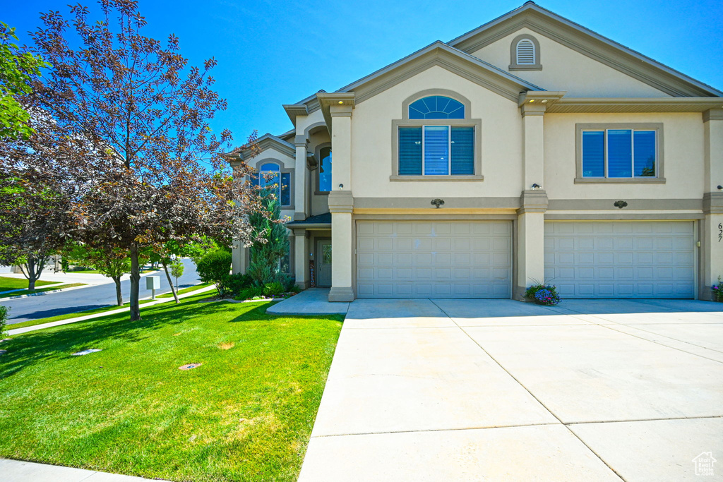 View of front facade featuring a garage and a front lawn