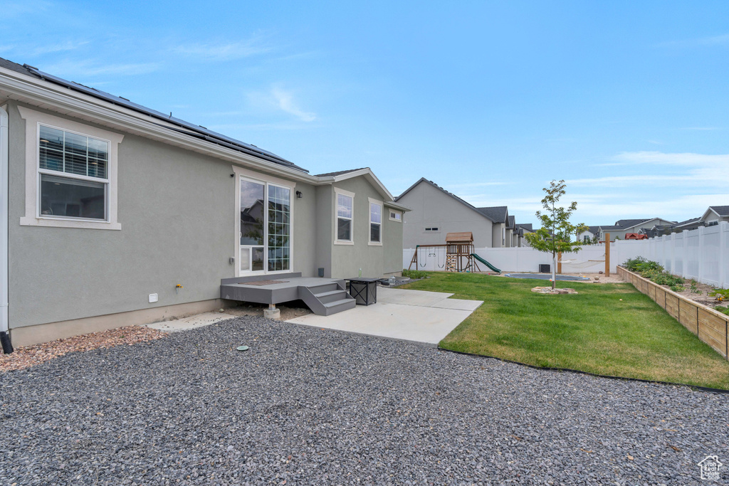 Back of property with a playground, a patio, and a yard