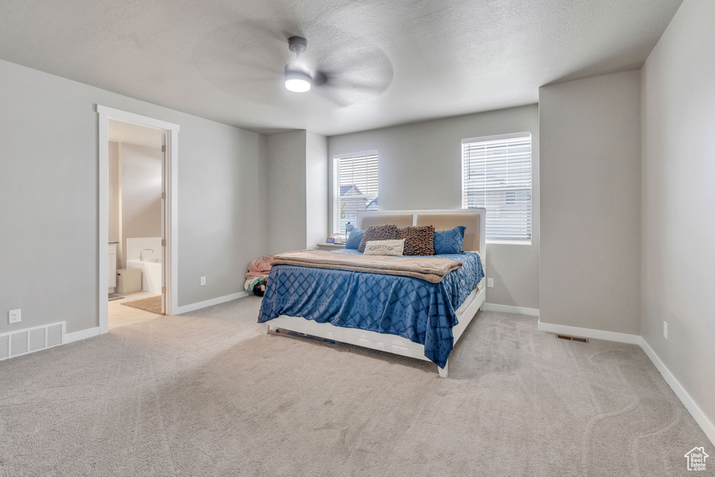 Bedroom featuring light carpet, ensuite bathroom, and ceiling fan