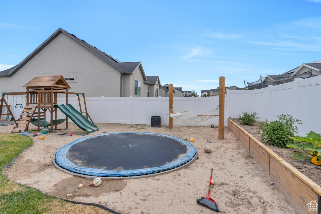 View of yard with a trampoline and a playground