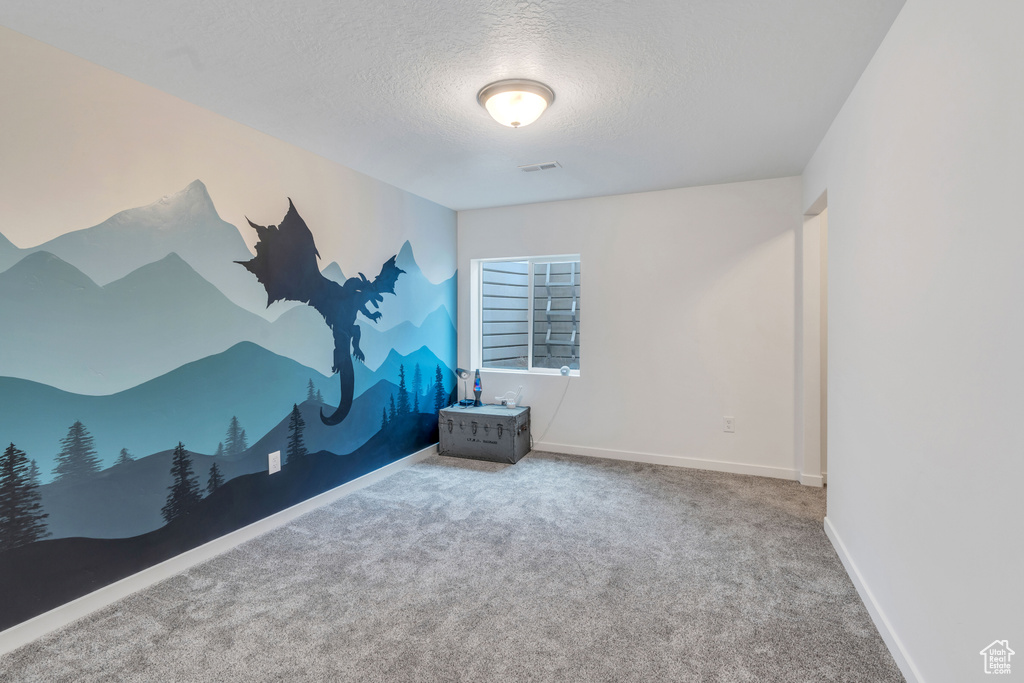 Carpeted empty room featuring a textured ceiling