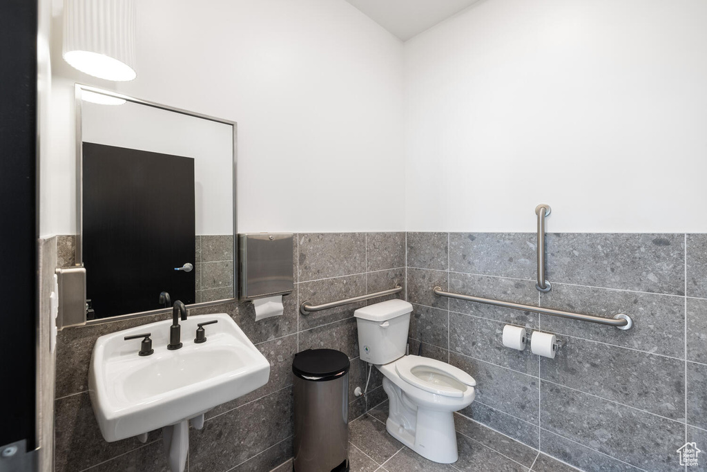 Bathroom featuring sink, tile patterned flooring, toilet, and tile walls