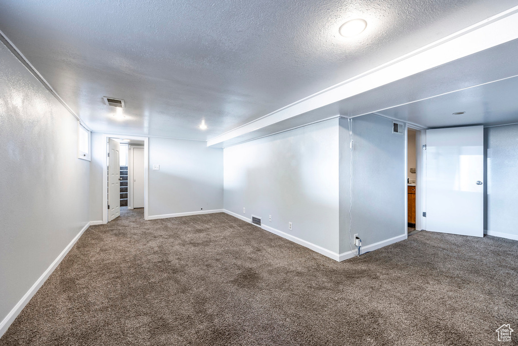 Basement with carpet flooring and a textured ceiling