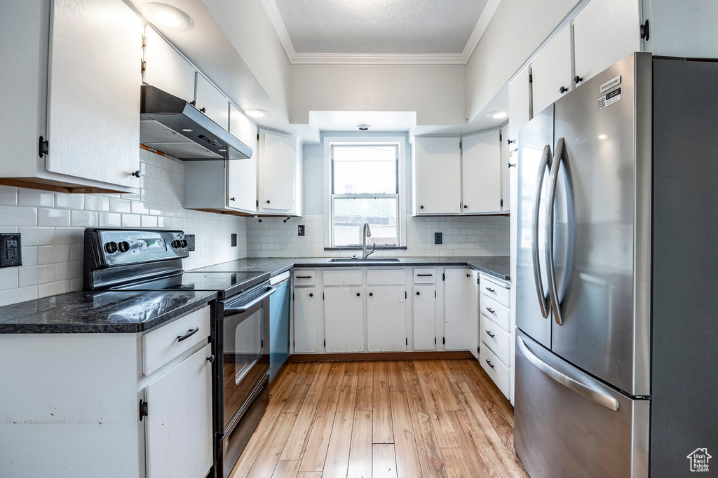 Kitchen with white cabinets, appliances with stainless steel finishes, and light wood-type flooring