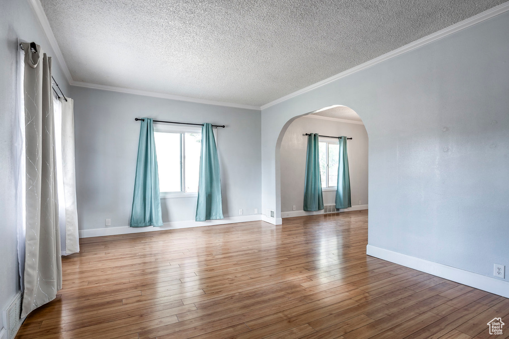 Unfurnished room featuring crown molding, a textured ceiling, and wood-type flooring