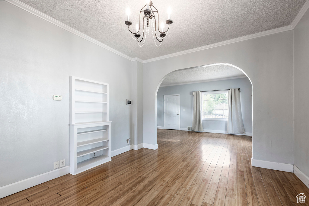 Empty room with ornamental molding, a textured ceiling, and hardwood / wood-style flooring