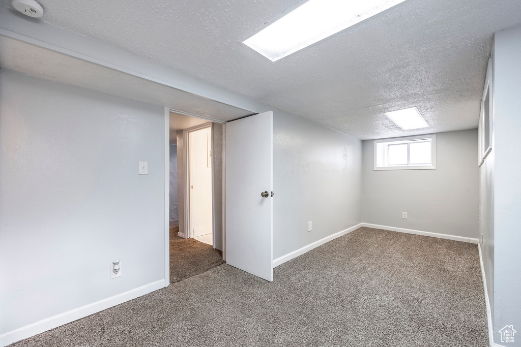 Basement featuring dark carpet and a textured ceiling