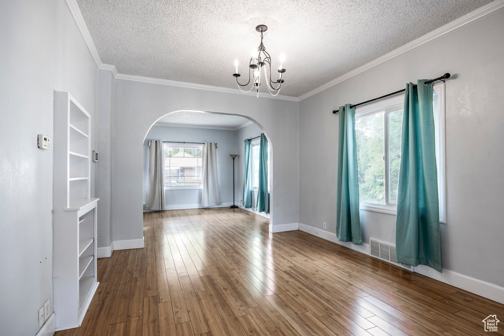 Interior space with crown molding, a textured ceiling, a chandelier, and wood-type flooring