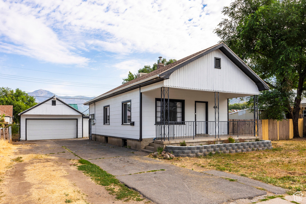 View of front of house with covered porch, an outbuilding, and a garage