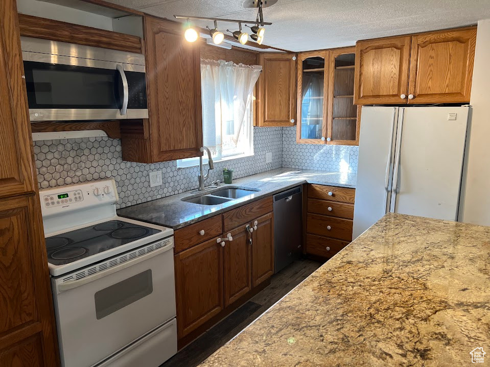 Kitchen with a textured ceiling, sink, appliances with stainless steel finishes, and decorative backsplash