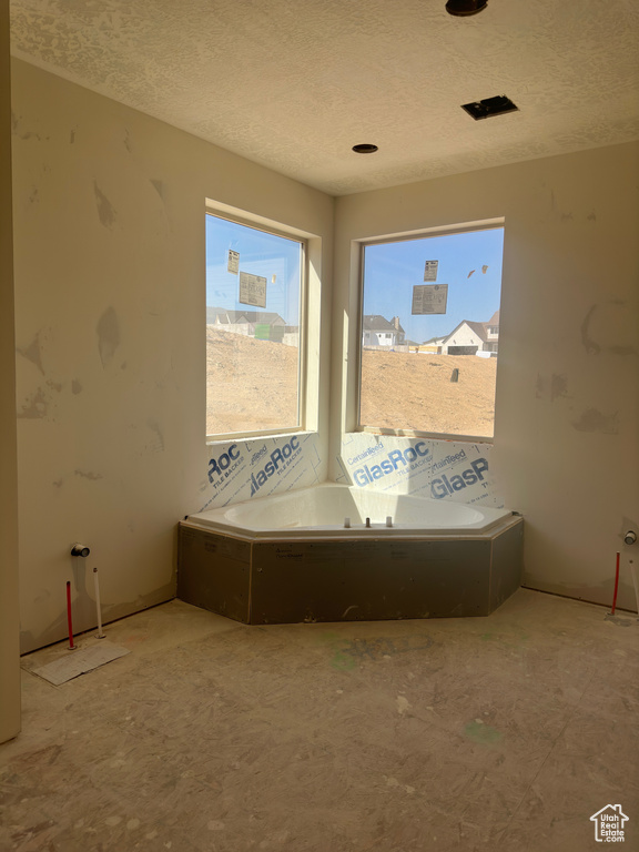 Bathroom with a tub and a textured ceiling