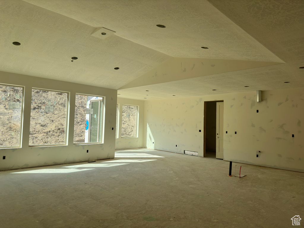 Empty room featuring a textured ceiling and vaulted ceiling