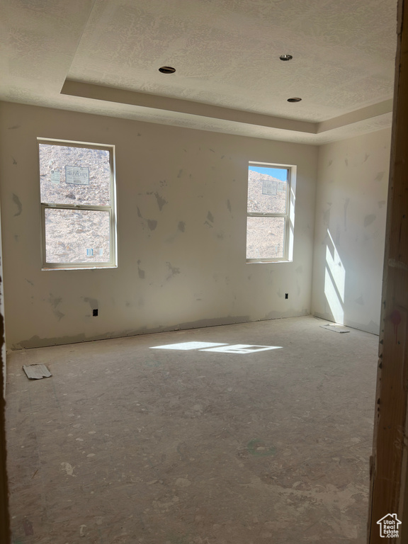 Unfurnished room featuring a raised ceiling and a textured ceiling